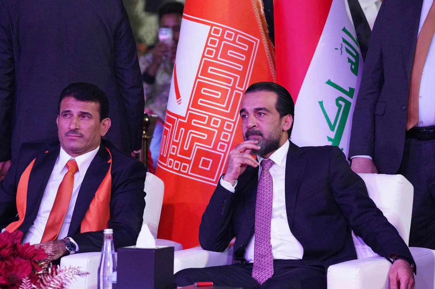 رئيس حزب تقدم إلى جانب راية الحزب والعلم العراقي