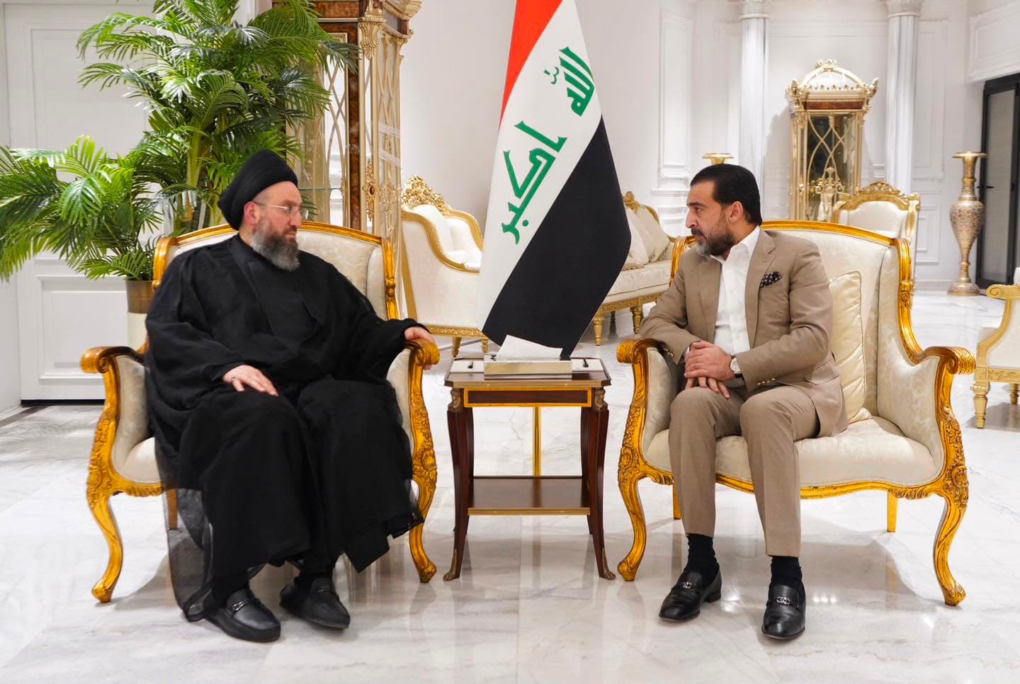رئيس حزب تقدم خلال استقباله رئيس تيار الحكمة الوطني إلى جوار العلم العراقي